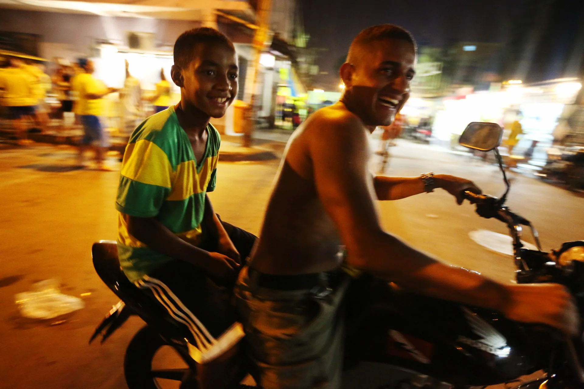 Breno and his friend ride through Maré in celebration