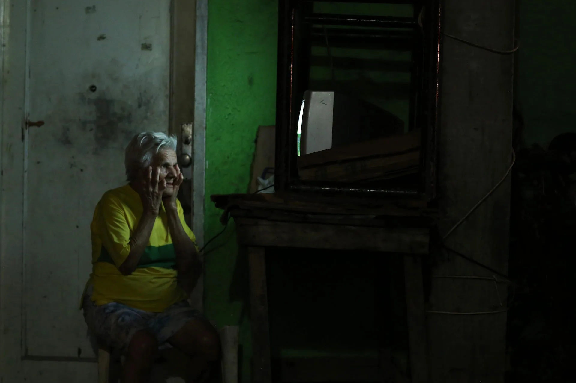 Dona Zefa watches the match in stunned silence outside her house